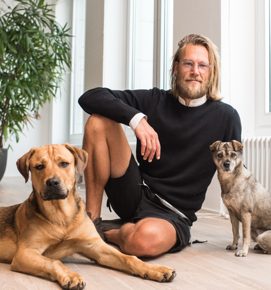 Lennard Hulsbos sitting on a wooden floor between two dogs